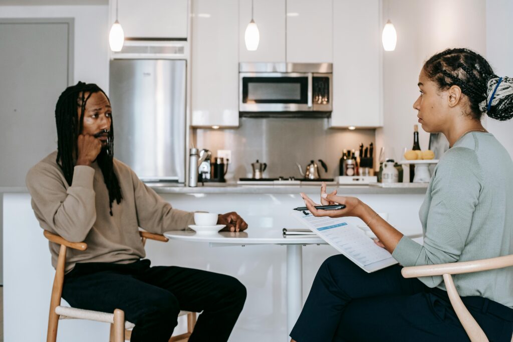 A therapist and client discussing in a contemporary kitchen, symbolizing mental health focus.